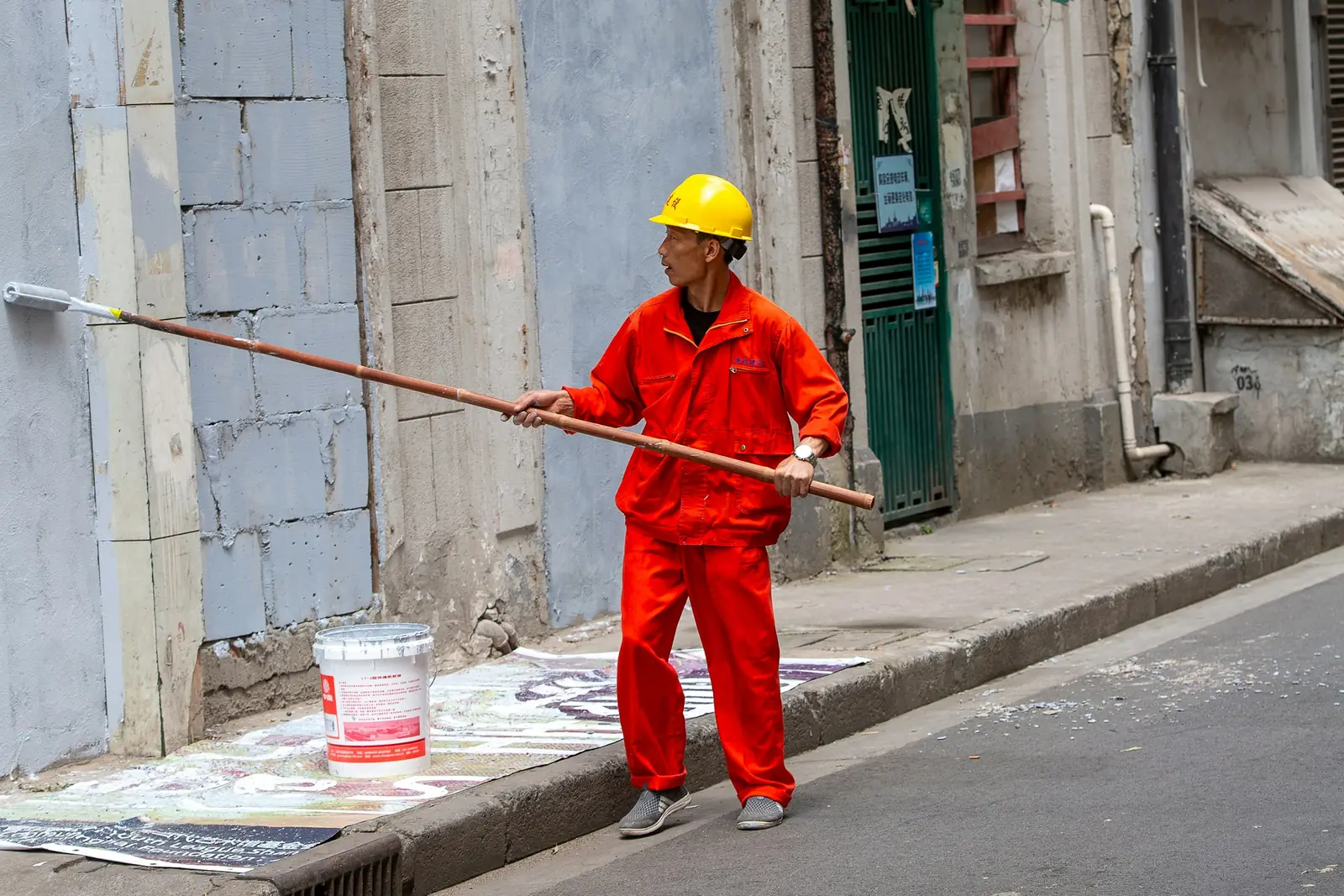 Painter in workwear painting an exterior building wall