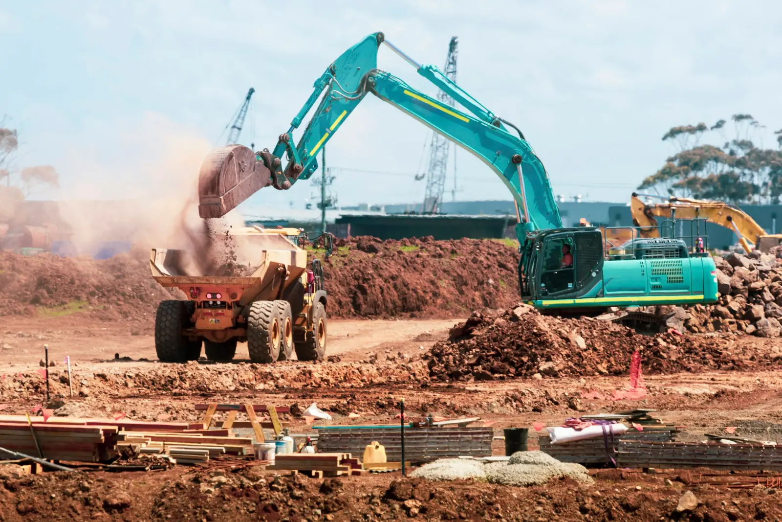 Excavator loading soil into a dump truck on a civil works site