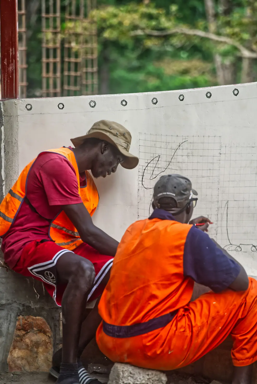 Two site workers in safety vests reviewing plans together