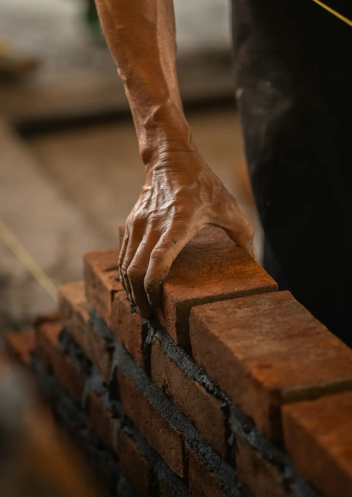Builder placing a brick onto a freshly mortared wall