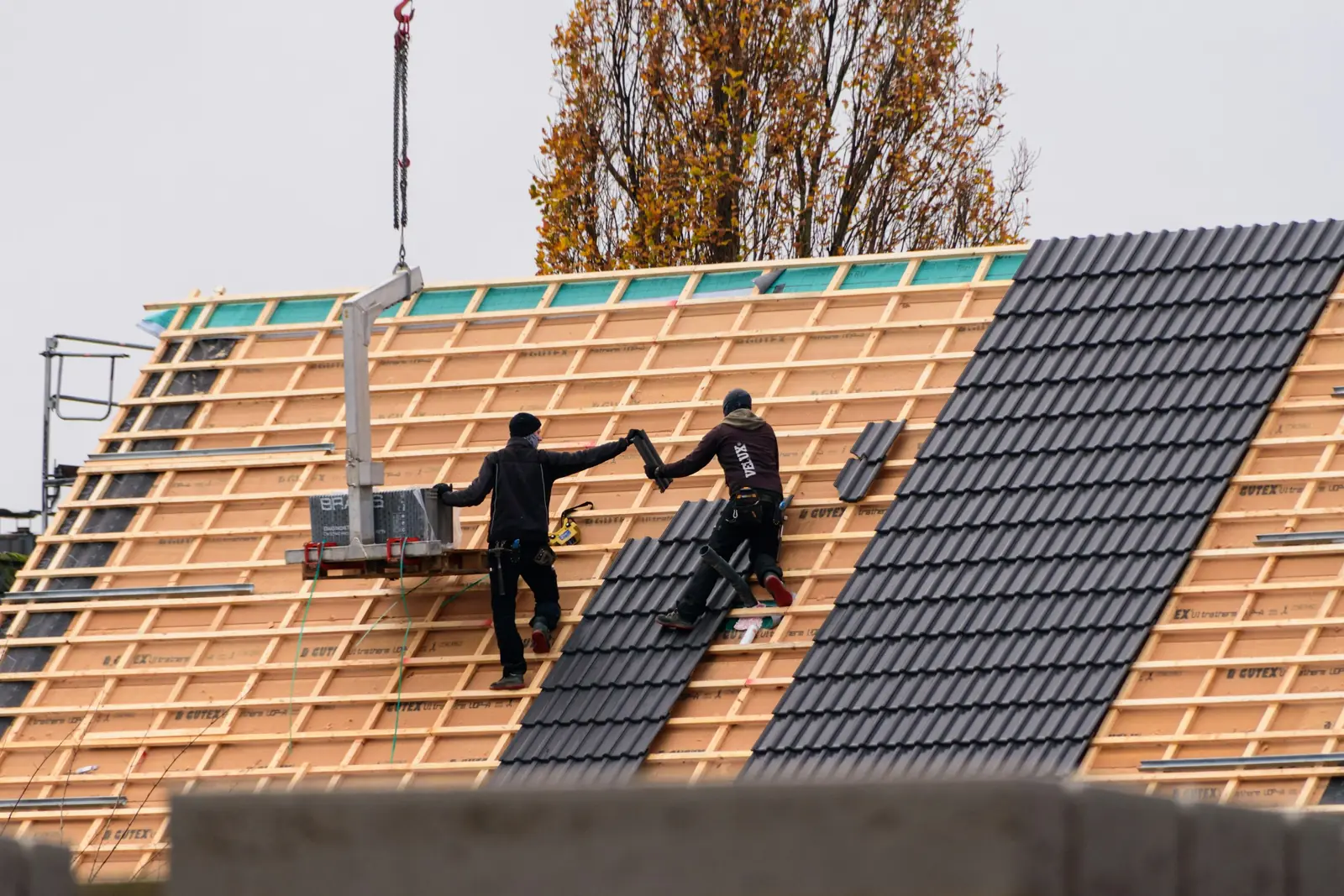 Roofers installing roof tiles on a new building