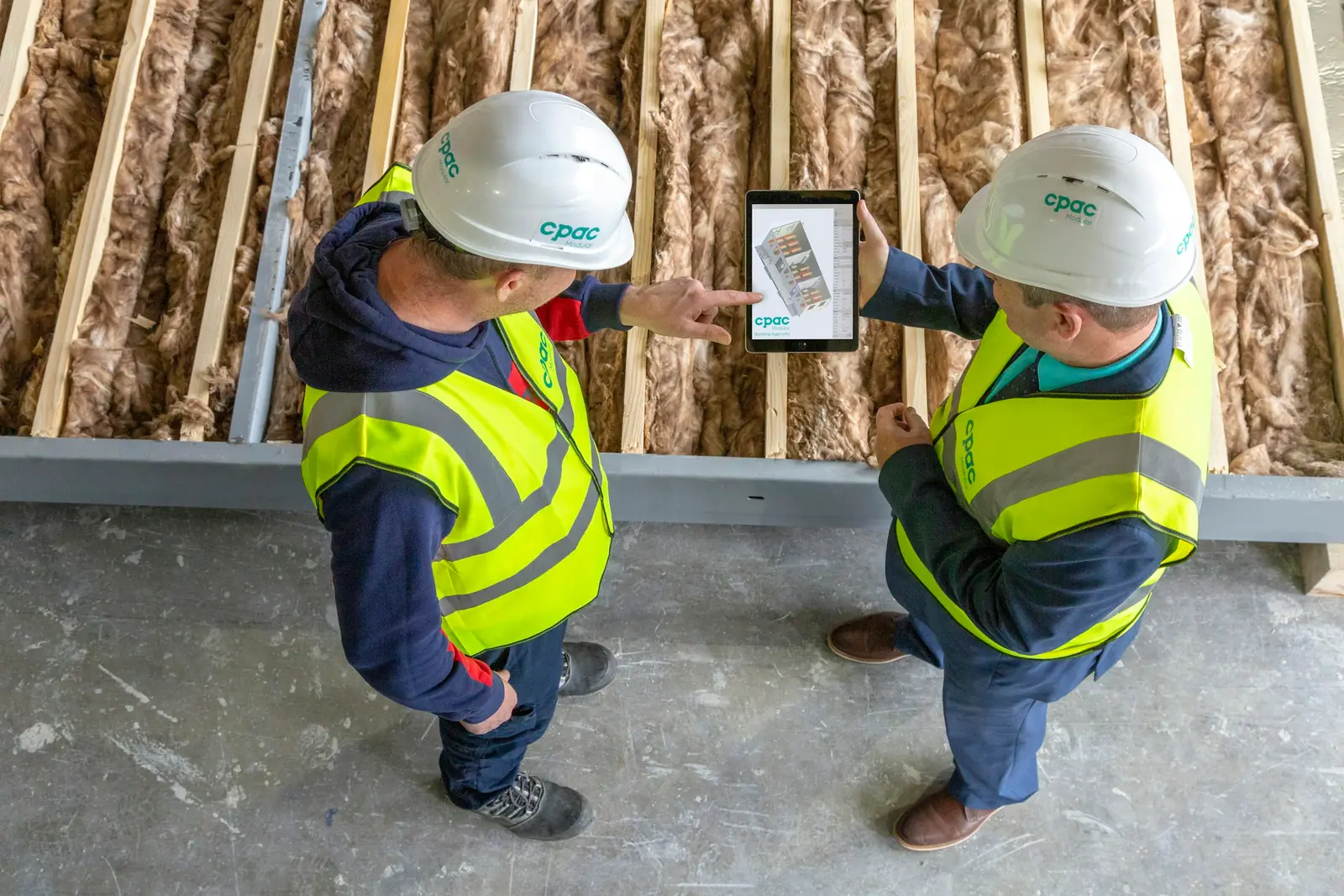 Two site workers reviewing plans on a tablet