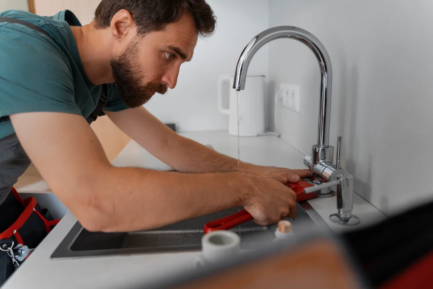 Plumber working on pipes beside a bathroom wall